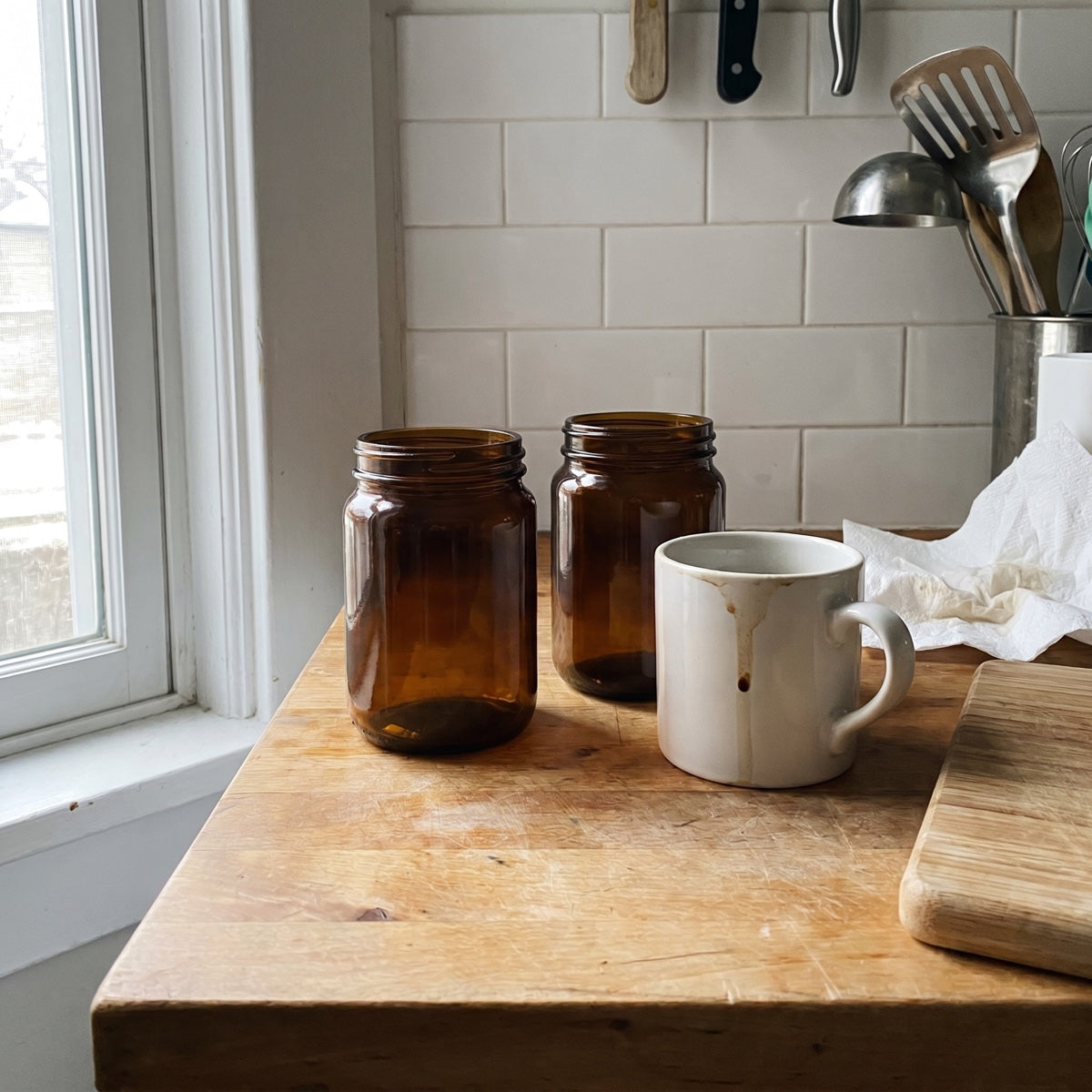 Two unlabeled amber supplement bottles on a home kitchen counter in soft morning light